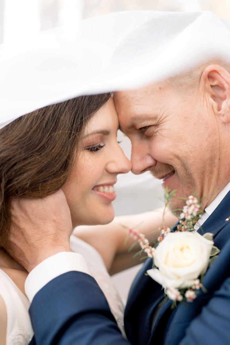 Couple sharing a tender moment under a white archway at a wedding in Brisbane.
