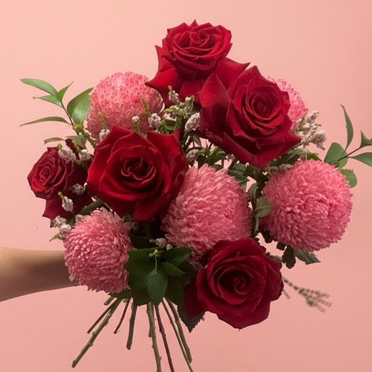 Bouquet of red roses and pink flowers on a pink background