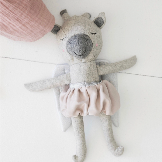 Stuffed animal toy with a pink skirt on a white surface