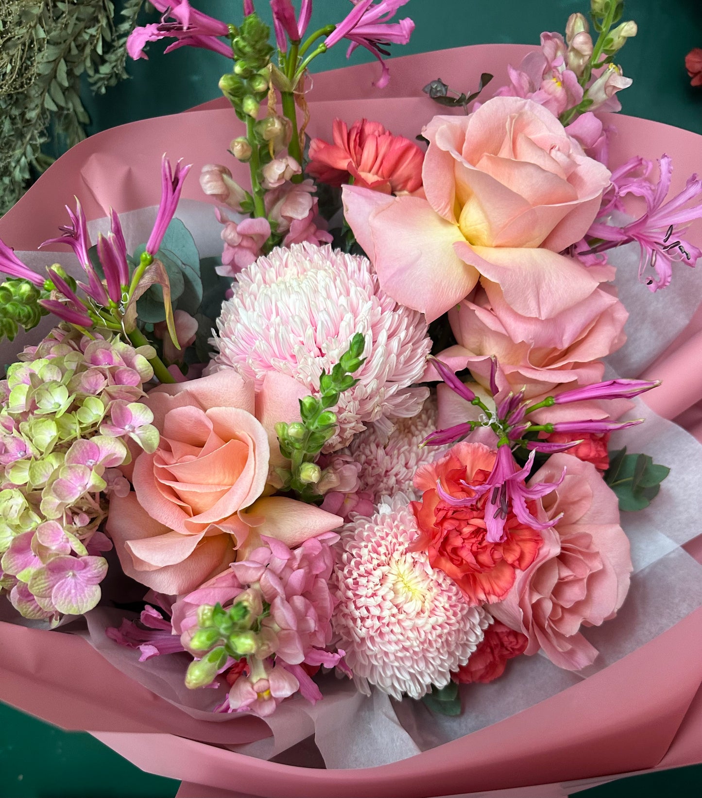 Bouquet of flowers with pink and green tones in a pink wrap.
