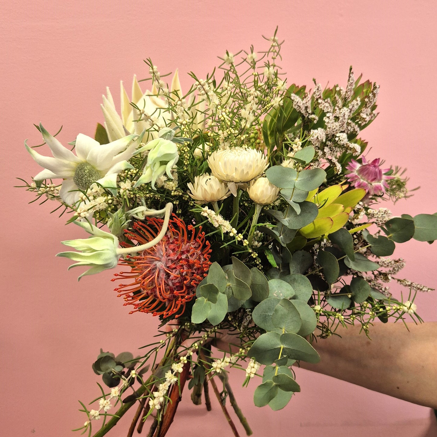 Bouquet of flowers with greenery against a pink background