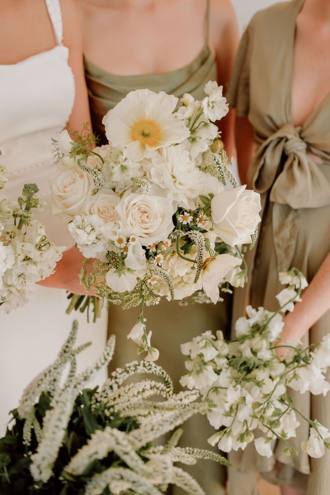 Bouquets of white wedding flowers held by people in green dresses. In Brisbane
