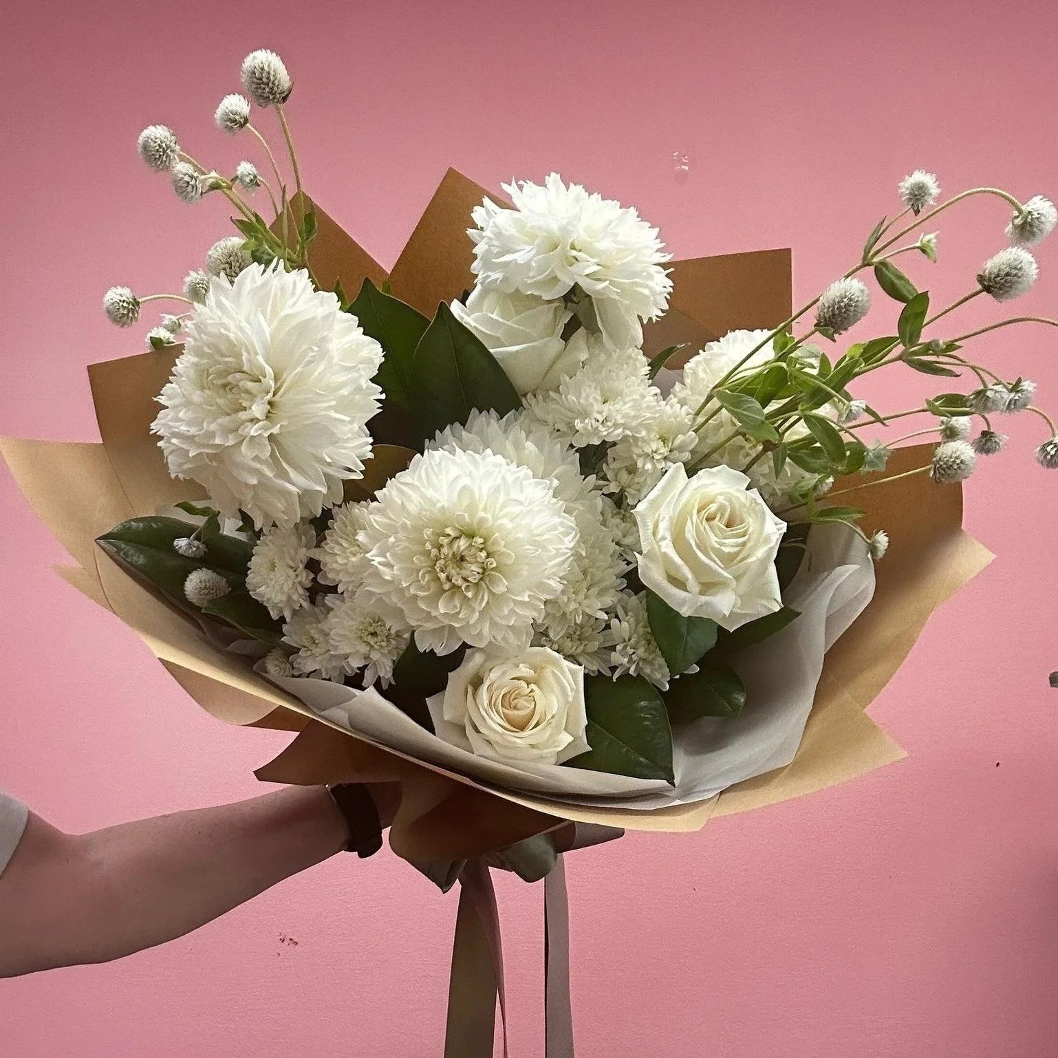 Bouquet of flowers whites and greens tones on a pink background